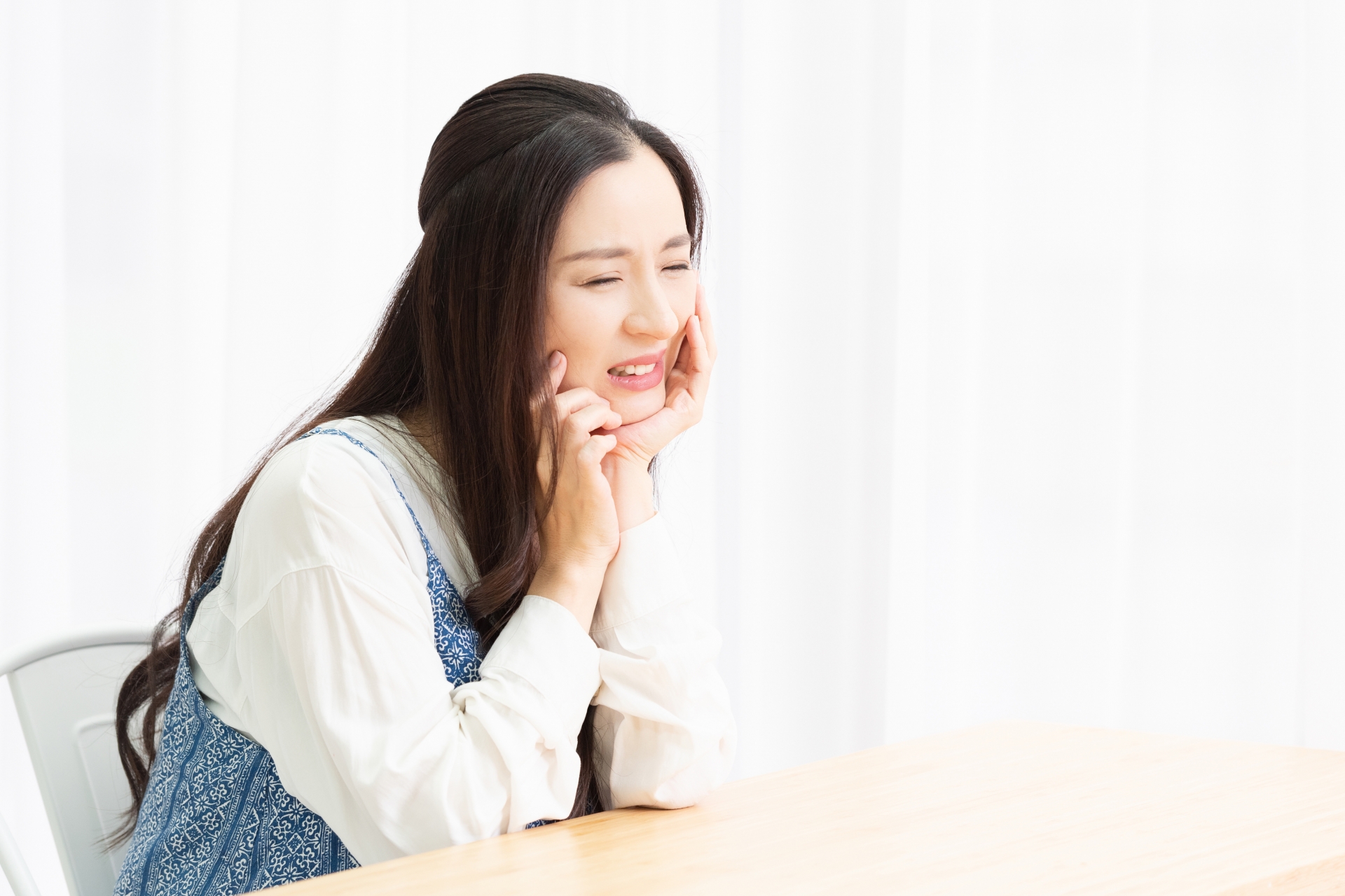 歯が痛くて頬に手を当てる主婦