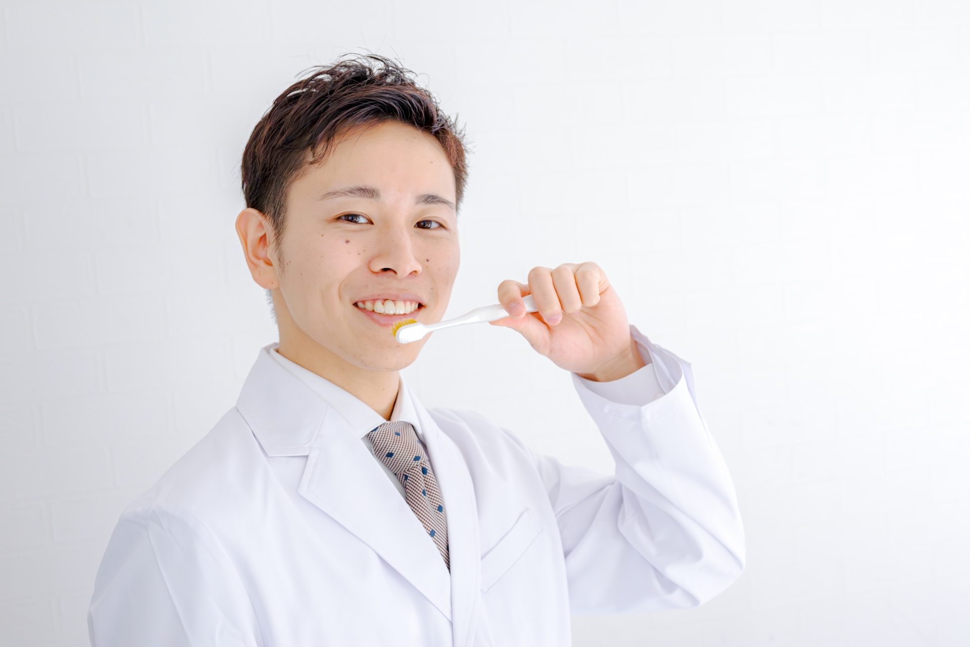 歯ブラシを持つ白衣男性