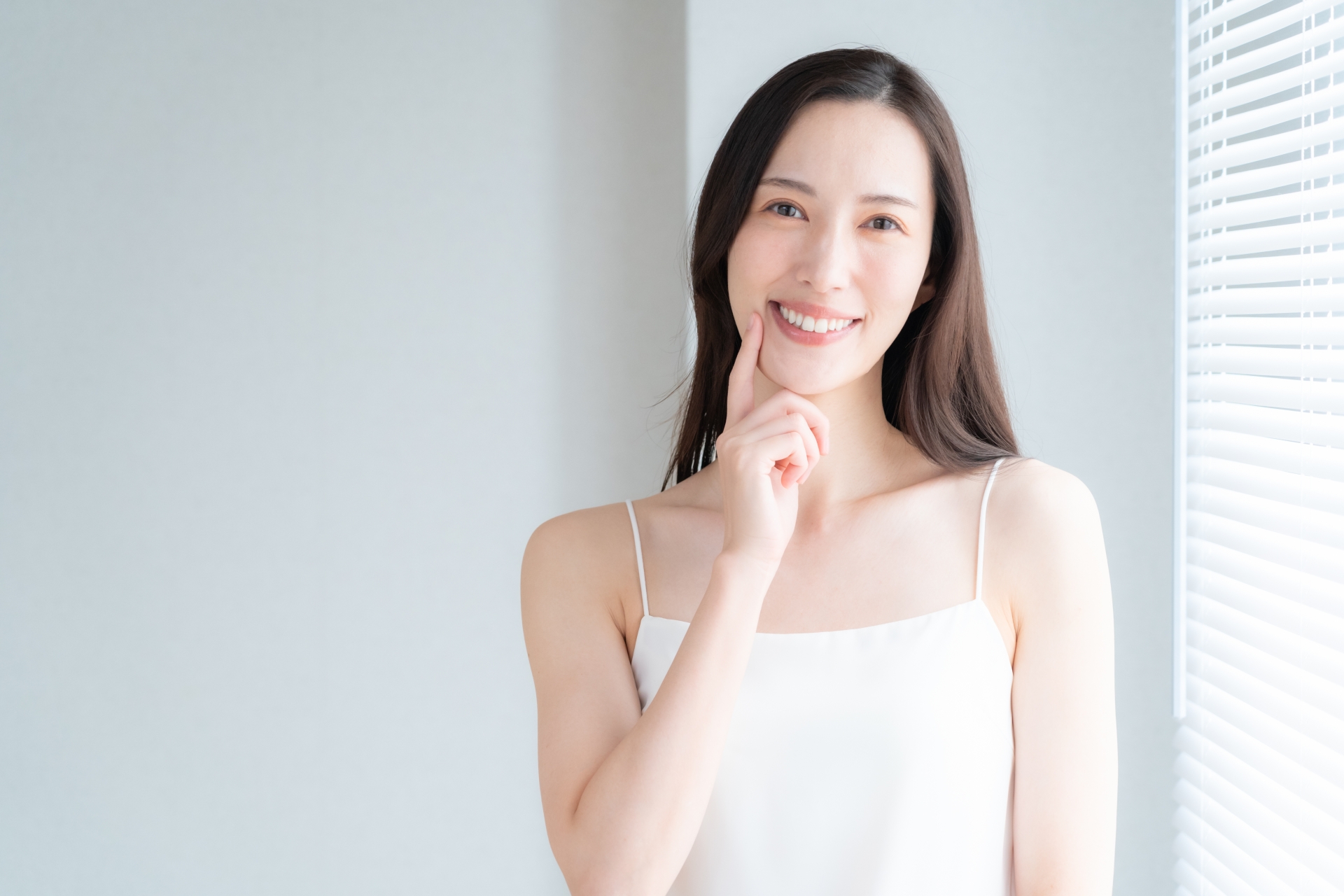 窓際でスキンケアをする若い女性
